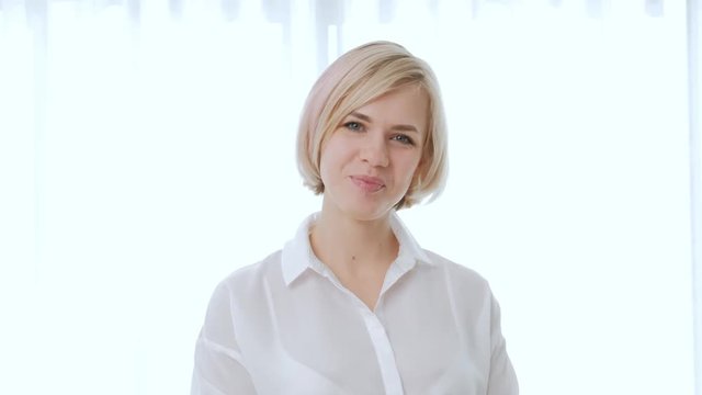 Young beautiful woman blonde with short hair in glasses on a white background. Clever and elegant, rejoices at the victory and carefully looks. Office life, businesswoman.