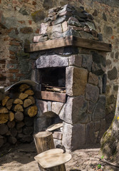 Stone fireplace for frying meat, laid out on the street against the wall, along with firewood.