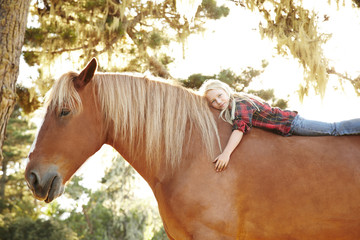 Portrait of little girl lying on horse in nature smiling
