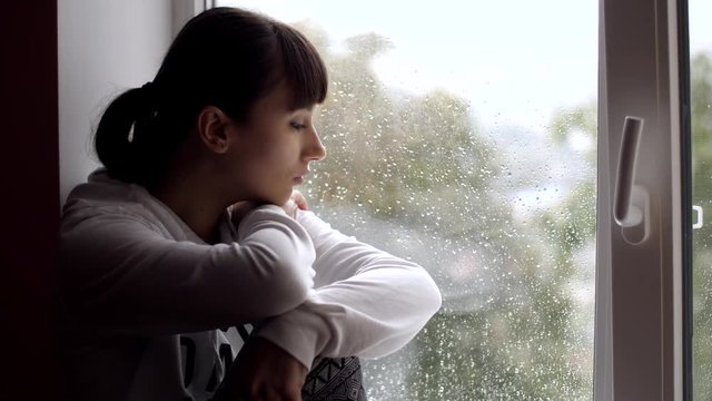Sad woman sitting on windowsill