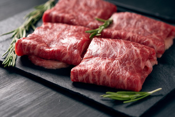 Sliced wagyu marbled beef for yakiniku on plate on black background, Premium Japanese meat, close up
