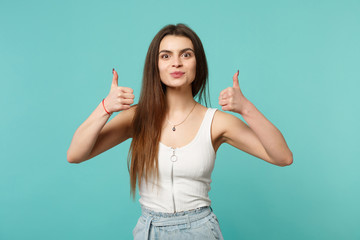Fototapeta premium Portrait of pretty attractive young woman in light casual clothes showing thumbs up isolated on blue turquoise wall background in studio. People sincere emotions lifestyle concept. Mock up copy space.