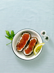 Fresh bread sandwich with red caviar and soft cheese on a plate. classic combination of ingredients. snack on the table