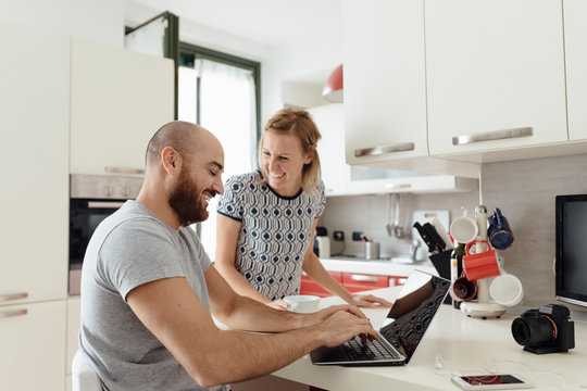Adult Couple Using a Laptop From a Kitchen during the Morning Breakfast