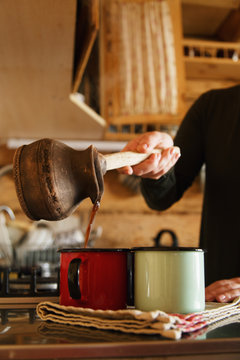 Unrecognizable person?pouring?coffee?cups from old?turk