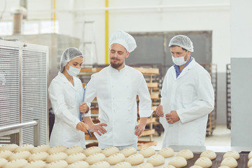 Technologist and baker inspect the bread production line at the bakery