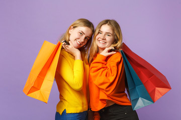 Two smiling young blonde twins sisters girls in vivid clothes ho