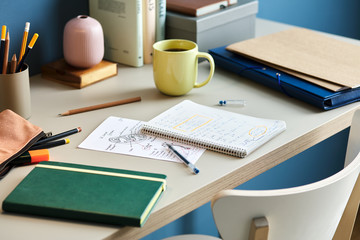 Student's desk with notes in notebooks and cup of drink in dayli