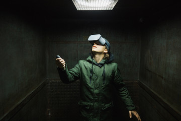 Young man using gray VR goggles finding himself in an industrial elevator