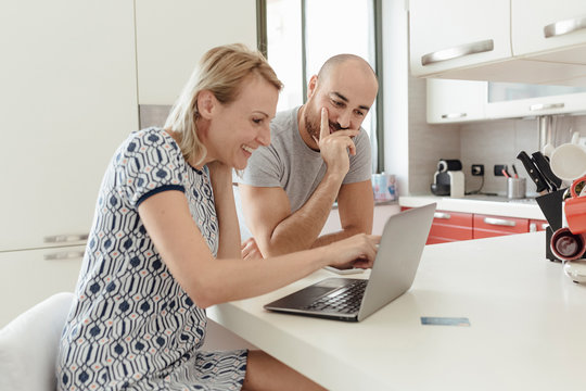Adult Couple Using a Laptop From a Kitchen during the Morning Breakfast