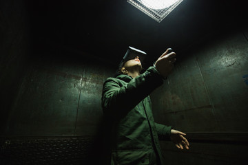 Young man using gray VR goggles finding himself in an industrial elevator