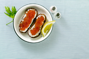 Fresh bread sandwich with red caviar and soft cheese on a plate. classic combination of ingredients. snack on the table