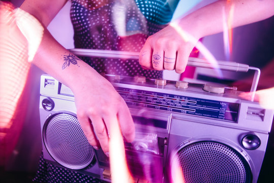 Close up of a womans hands putting a cassette tape into a ghetto blaster