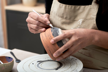 Artisan decorating clay pot with tool