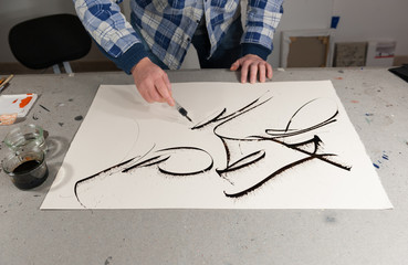 A Master Calligrapher using a siringe to draw marks on a paper