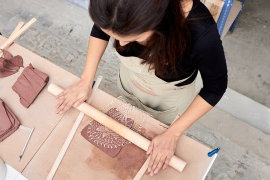 Woman rolling piece of clay on table