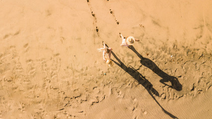 Couple of young woman have fun at the beach in summer holiday vacation at the resort - vertical top view and nice shadows - people having fun together in friendship - sandy lifestyle