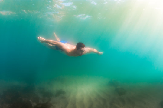 Man dives to explore shallow water with sandy bottom