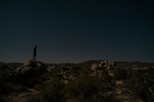 A young man sitting under the night sky in Joshua Tree National Park
