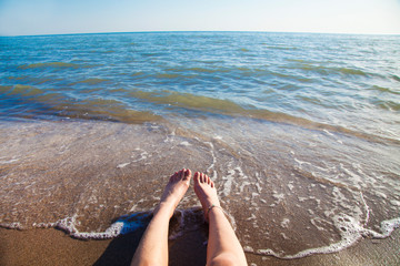Lower half of the girl body lying on the beach by the sea