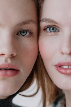 Closeup beauty portrait of two half-faces of pretty young models with blue eyes  looking at camera