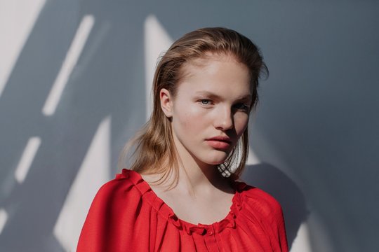 Pretty blond in red blouse posing indoors in contrast daylight