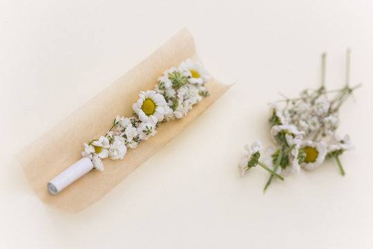 420 concept showing anonymous womans hands rolling spring flowers in cigarette paper