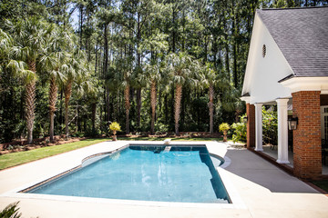 Large Blue Swimming Pool Outdoors with Brick Pool House and Home with pool Cleaner running