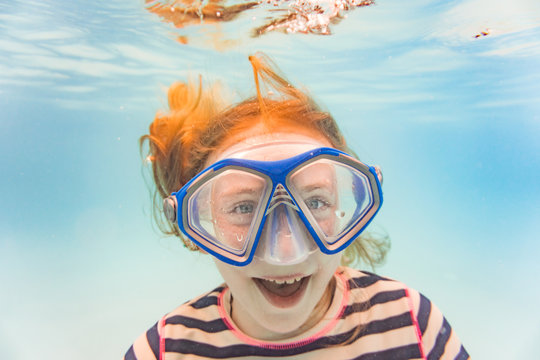 Girl On Family Vacation Has Fun Laughing In Diving Mask Underwater In Pool