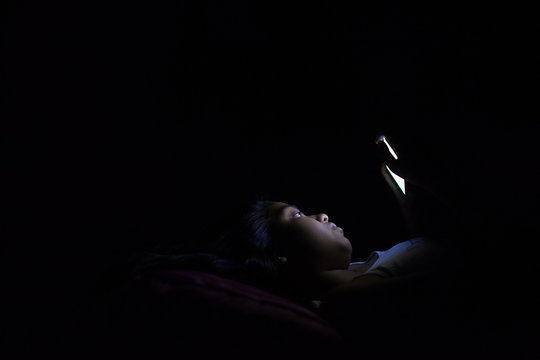 Teenage girl lying on the bed and browsing internet in smartphone
