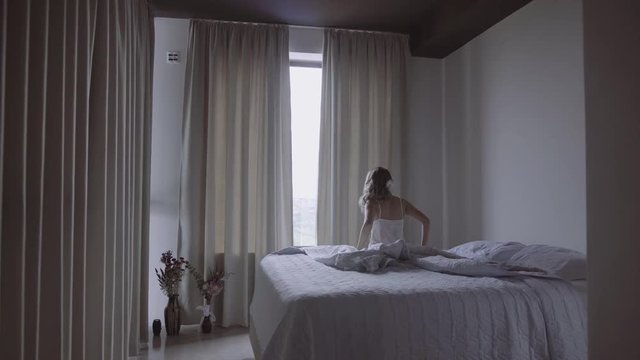 Girl waking up and walking towards the window