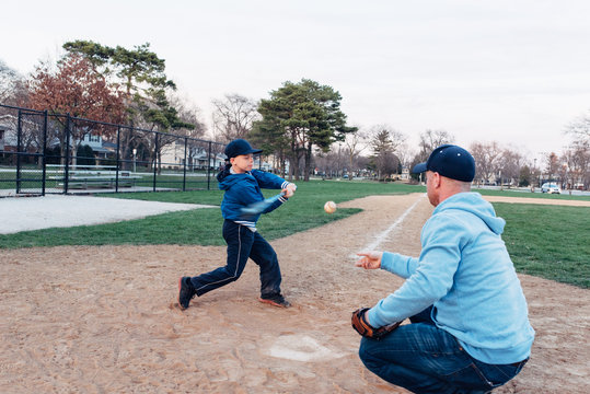 Father and son practicing hitting ball on a baseball field - Powered by Adobe