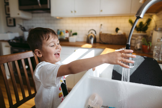 Happy little boy helping wash the dishes