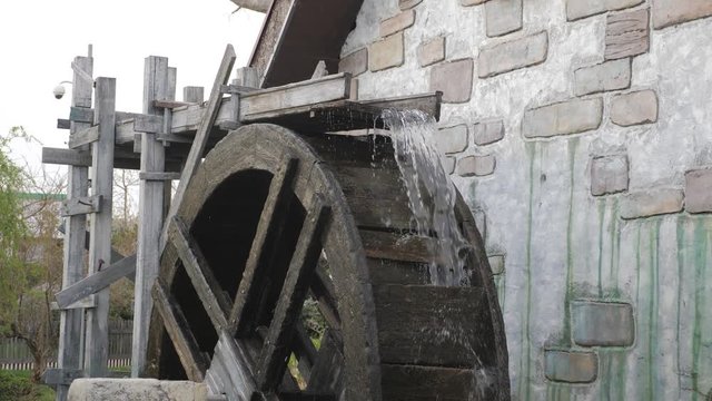 Wooden wheel of an ancient water mill on river.