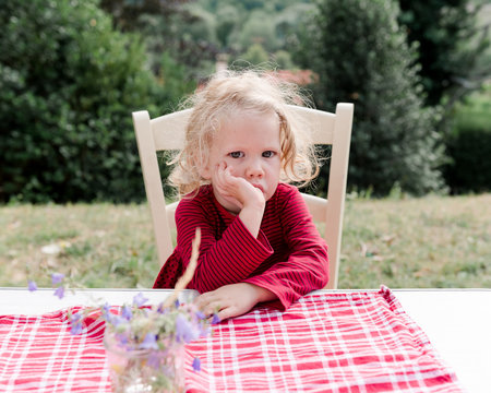 tired little girl sucking her thumb hile looking at camera
