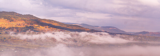 Carpatian village at mountains at the sunny foggy day