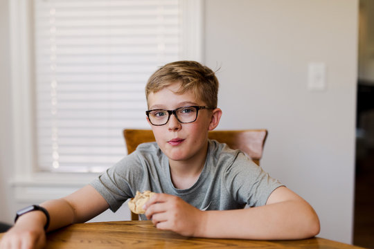 11 year old boy enjoying a snack at the kitchen table