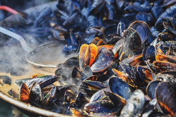 Mussels roasted on a grill pan. Seafood cooked outdoors. Selective focus
