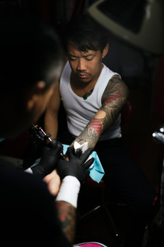 Professional asian tattooer makes a tattoo.