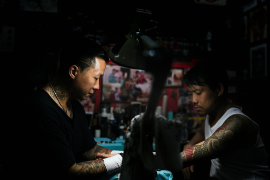 Professional asian tattooer makes a tattoo.