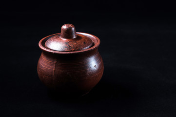 Brown clay lid for a pot made of honey on a black background