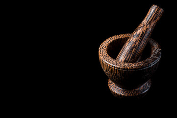 Wooden mortar and pusher for grinding kitchen spices, on a black background, isolate