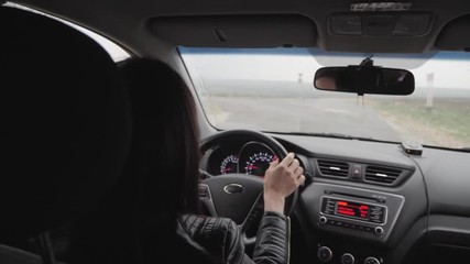 The girl was driving while the rain was falling. Driving on the road at heavy rains should be cautious. Heavy rains on road. Need more security than usual.