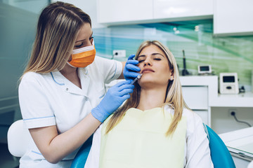 Fototapeta premium Attractive young woman is getting a rejuvenating facial injections. Medical procedure with hyaluronic acid.