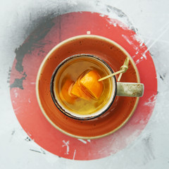 A cup of citrus tea with mango and orange slices on an orange saucer in a Japanese cafe. View from above.
