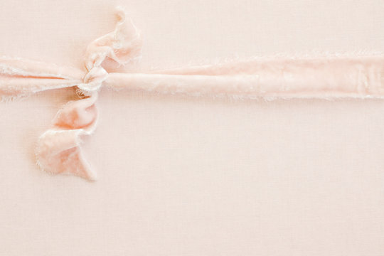 blush velvet ribbon knotted over blush linen background