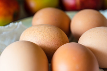 Brown fresh eggs macro shot with apples in back background. Close up
