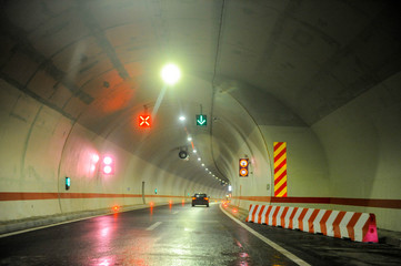 Modern new tunnel on a highway illuminated with lights and traffic signs