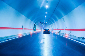 Modern new tunnel on a highway illuminated with lights and traffic signs