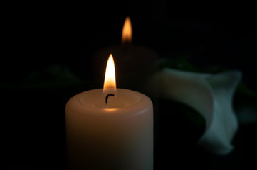 Close up of orange candle flame and lily flowers